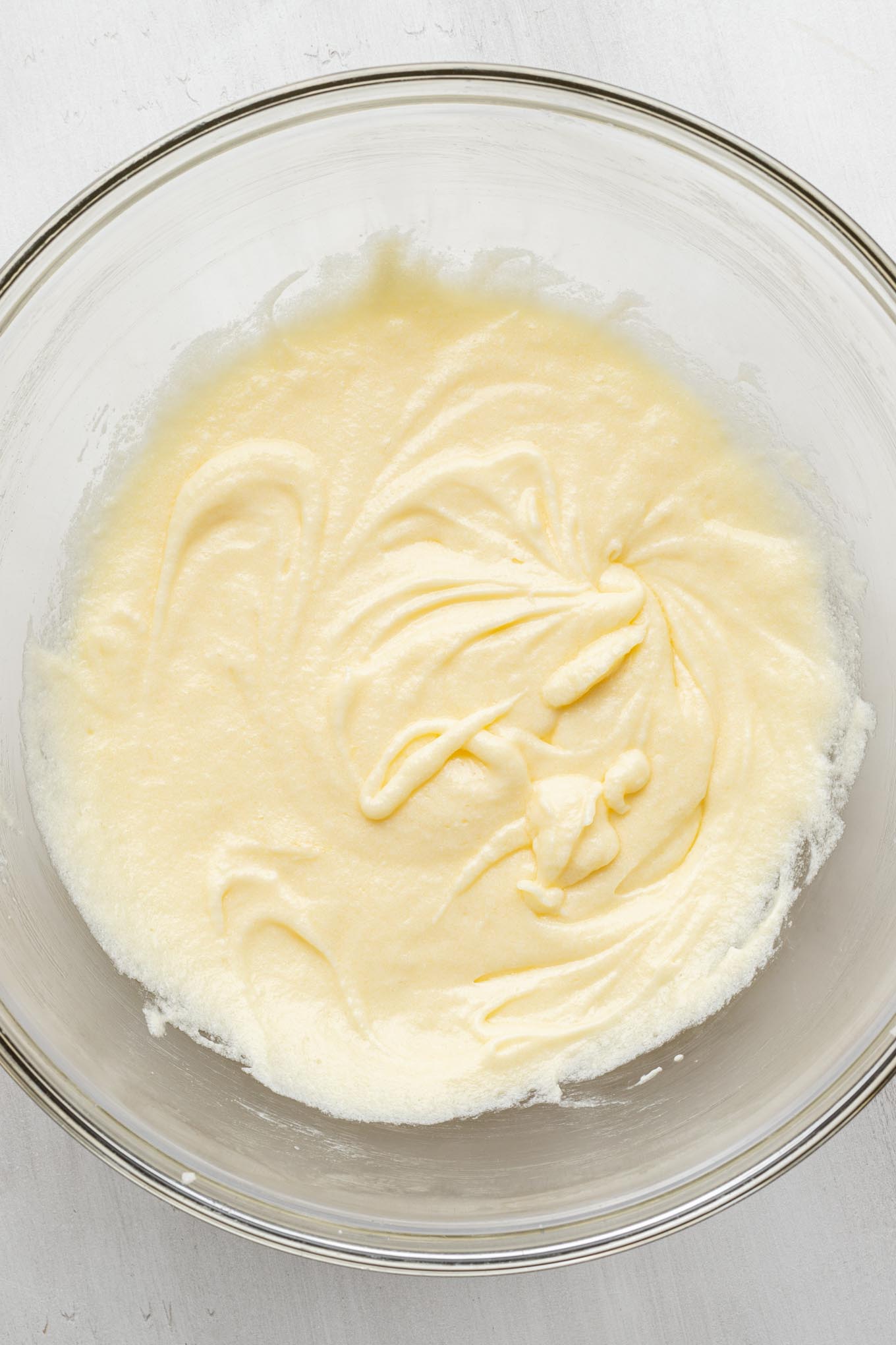 An overhead view of the wet ingredients for a vanilla cake in a glass mixing bowl.