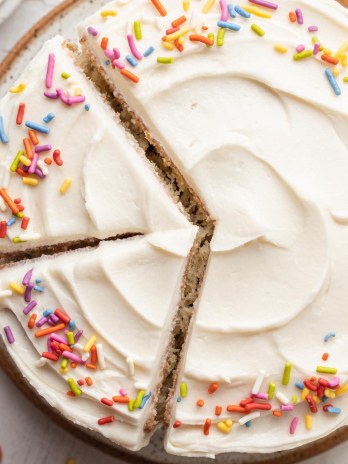 An overhead view of a 6 inch vanilla cake topped with sprinkles.