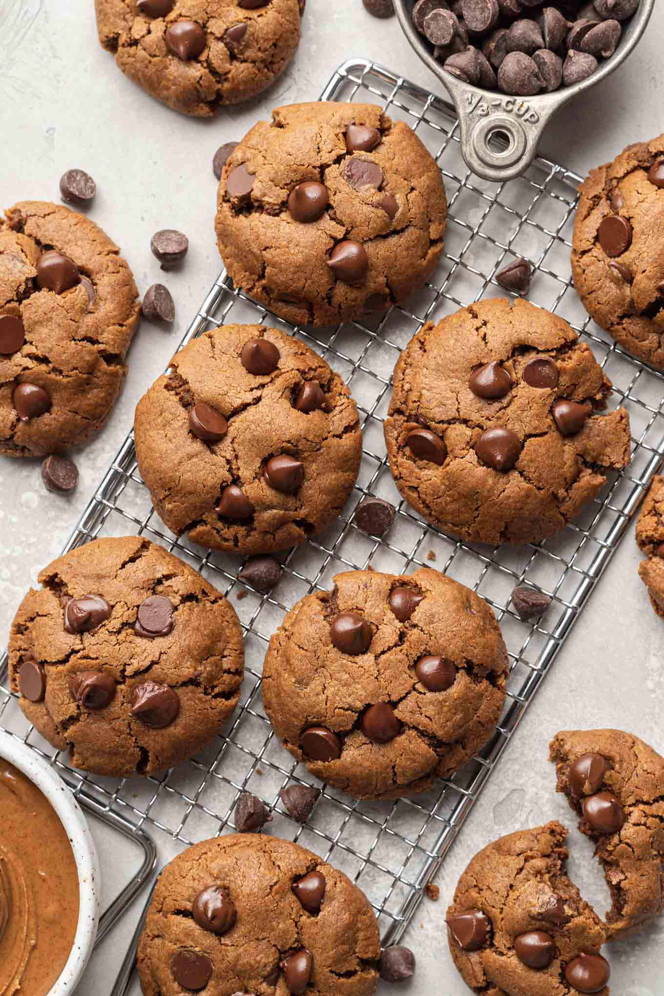 An overhead view of chocolate chip almond butter cookies on a wire rack. 