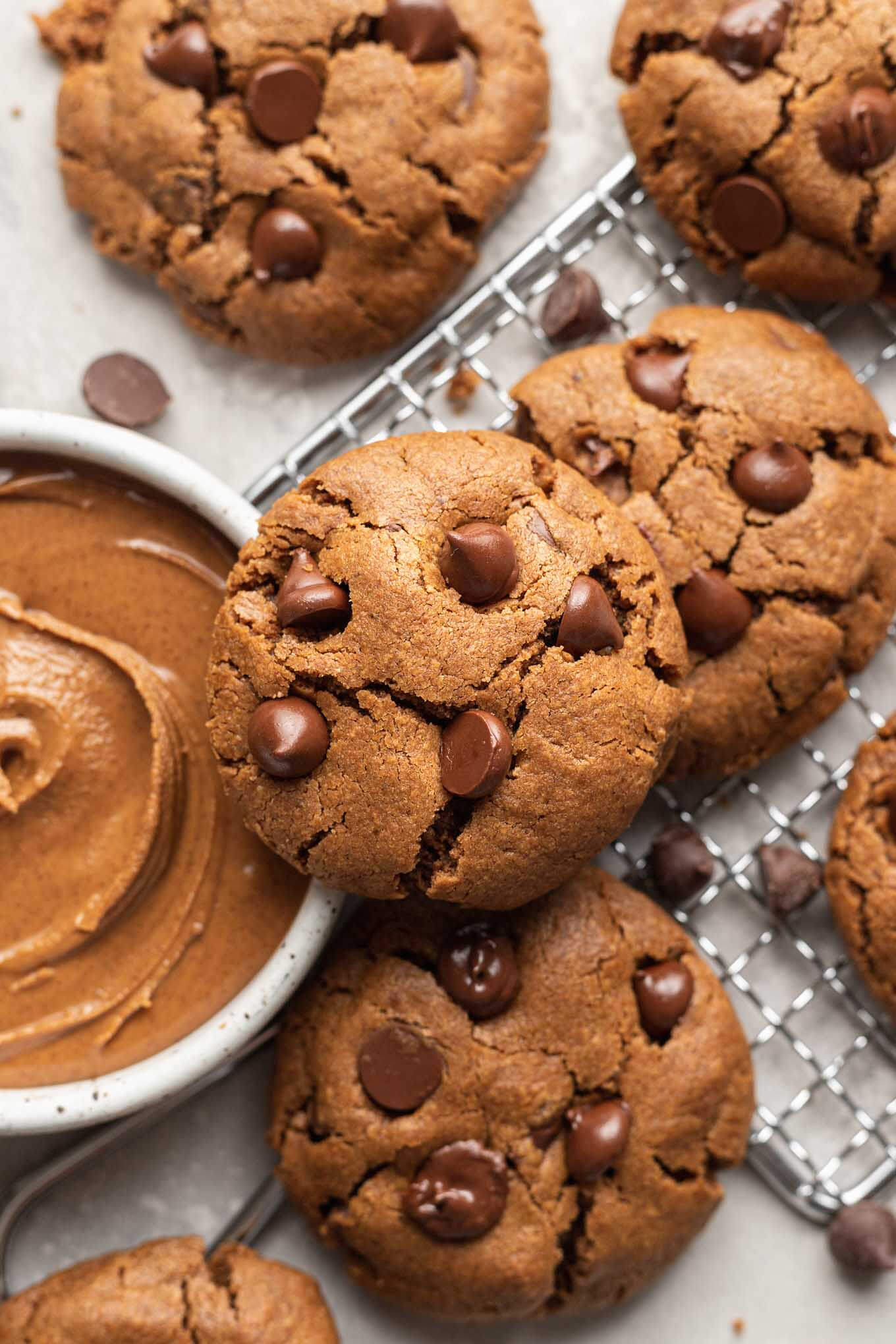 An overhead view of almond butter cookies, next to a bowl of almond butter. 