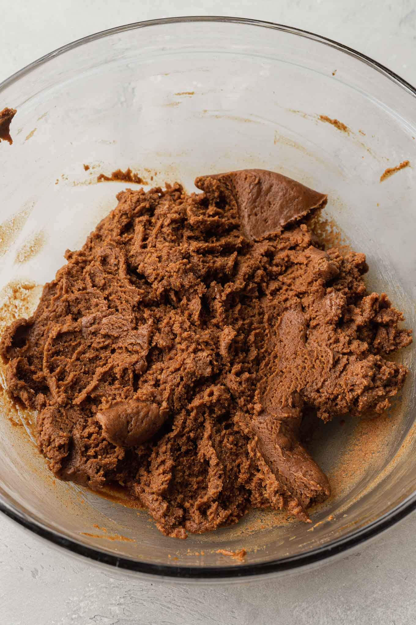 An overhead view of almond butter cookie dough in a mixing bowl.