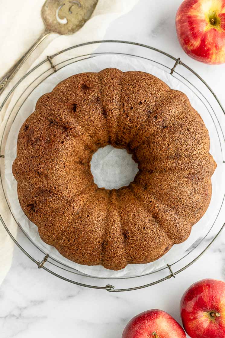 An apple cake sitting on top of a round wire rack.