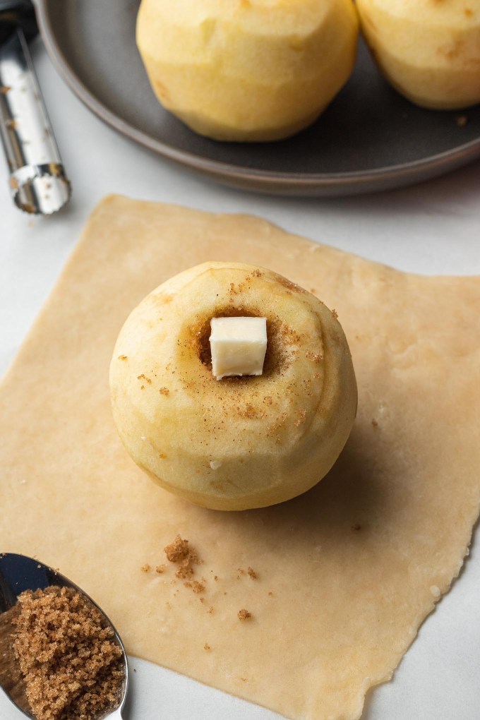 A peeled, cored apple stuffed with filling on a square of pie dough.