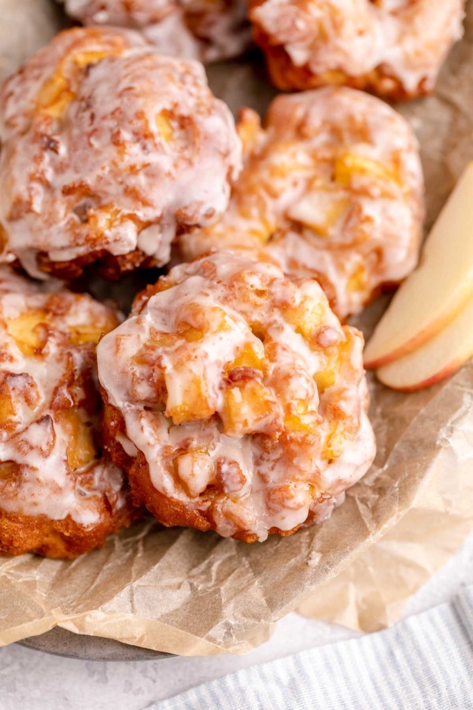 Homemade apple fritters in a parchment-lined bowl. 