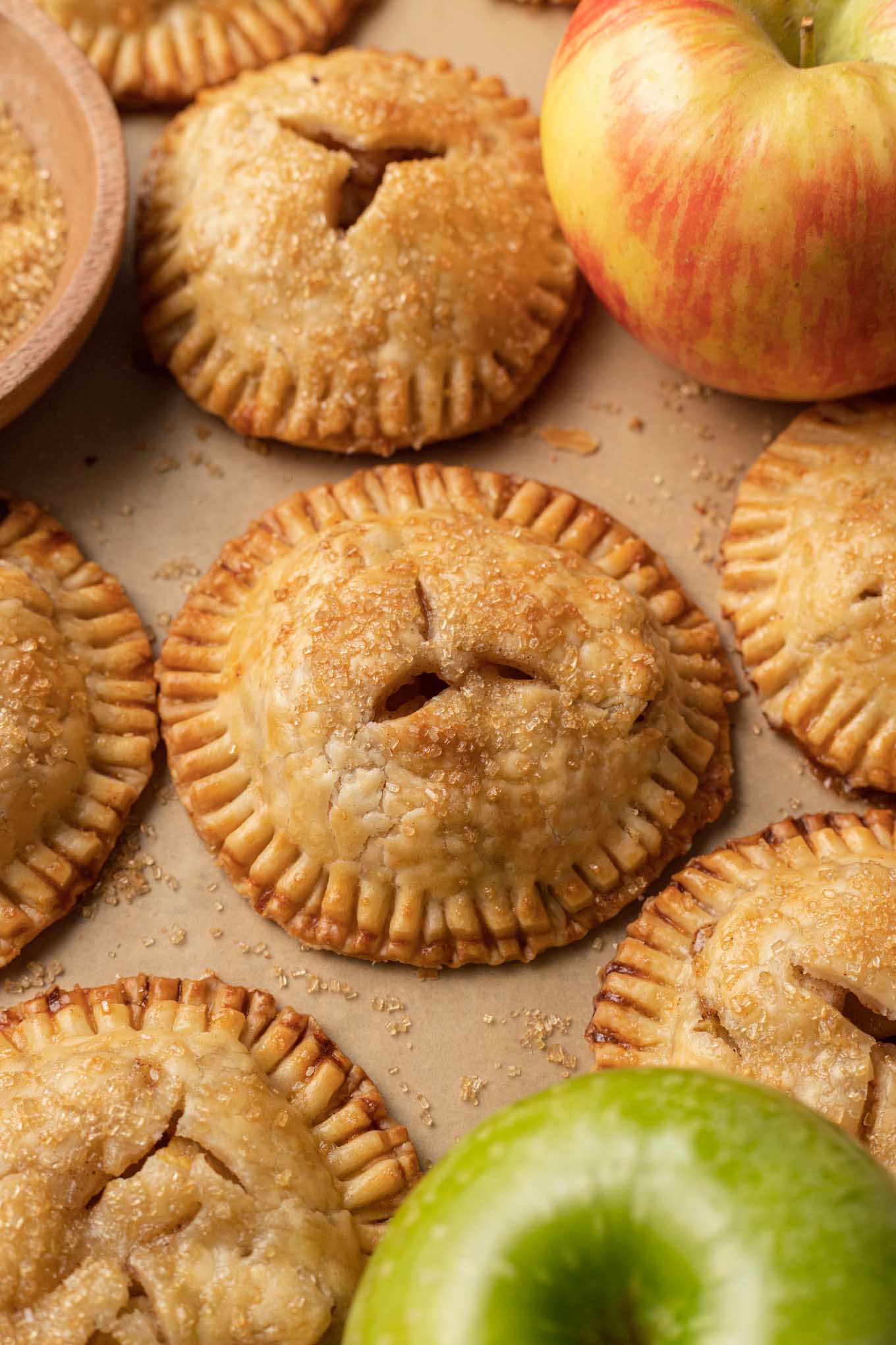 Golden brown hand apple pies on a parchment paper-lined baking sheet. 