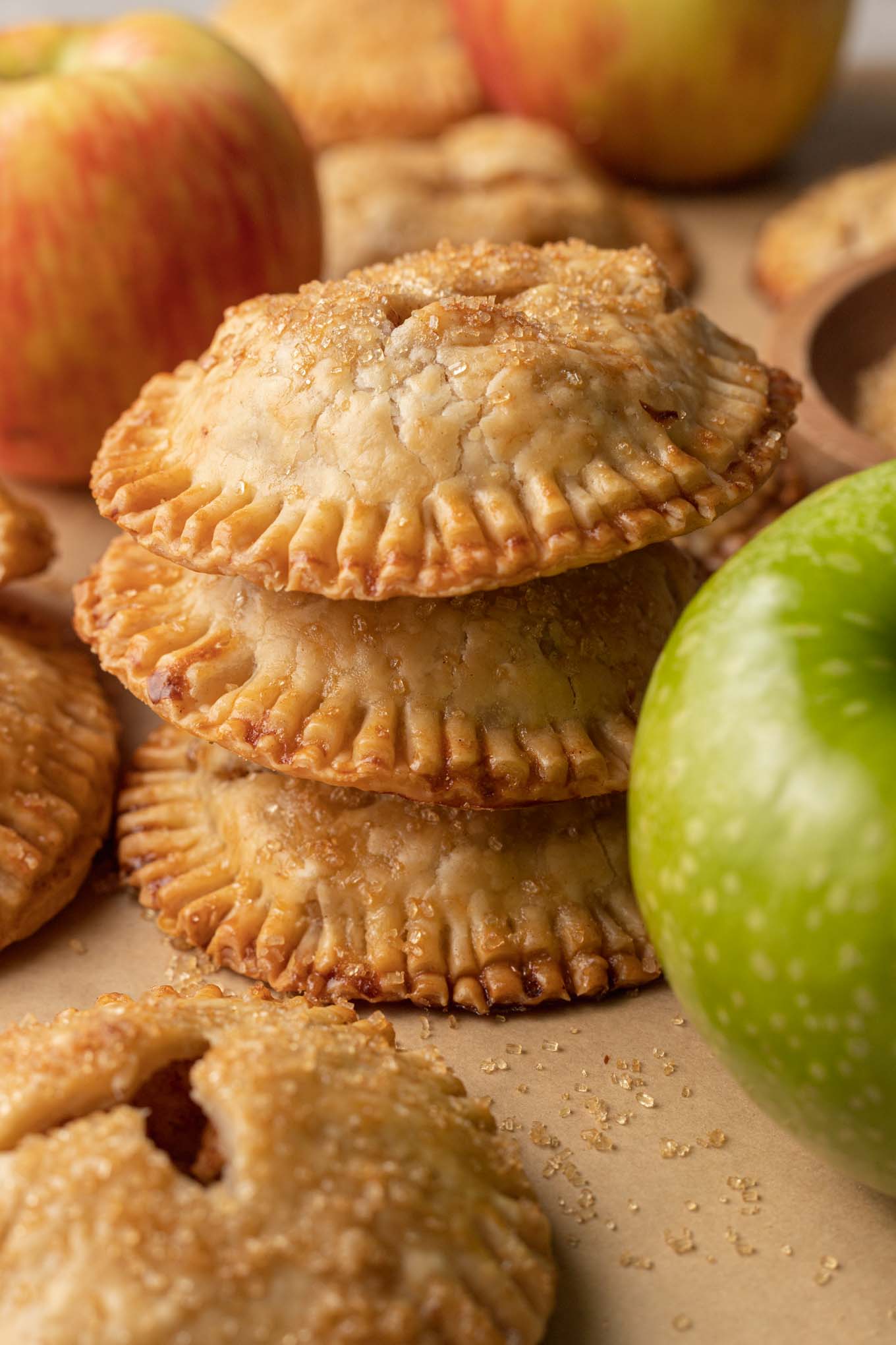 A stack of three apple hand pies, with a Granny Smith apple in the foreground. 