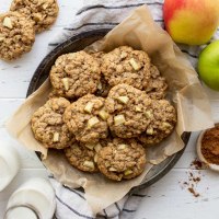 An overhead image of cookies in a metal baking dish surrounded by apples and cinnamon.