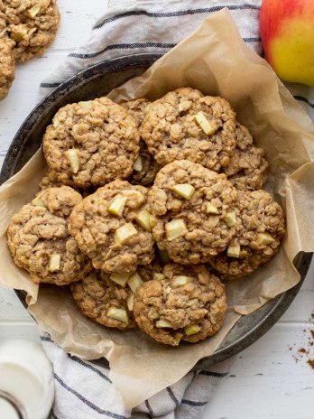 An overhead image of cookies in a metal baking dish surrounded by apples and cinnamon.