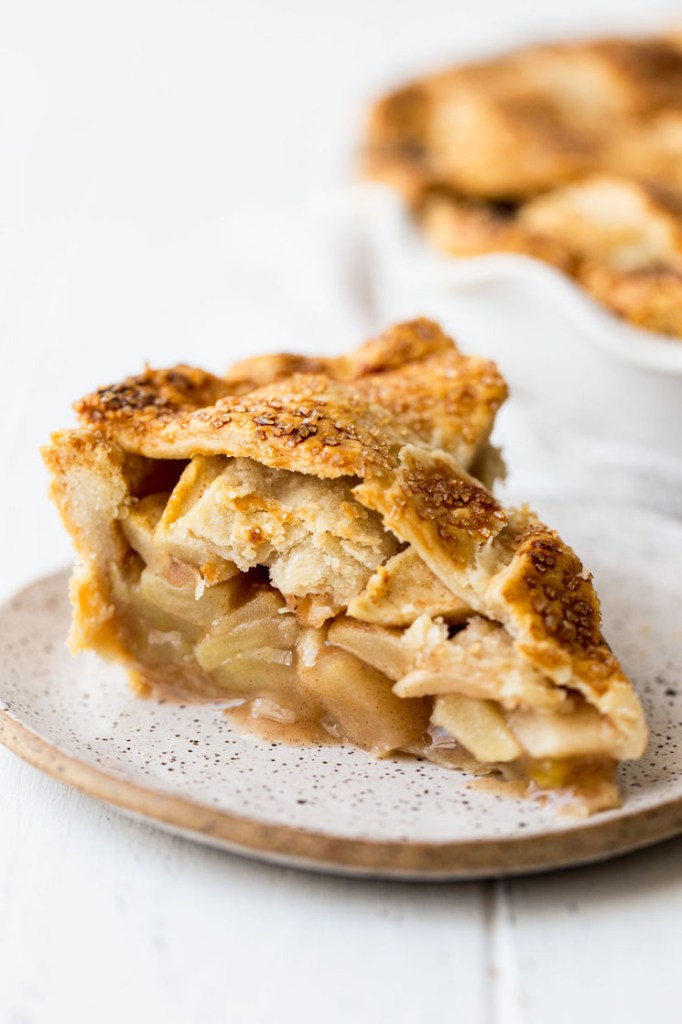 A close up image of a single slice of apple pie showing the crust and apple layers.