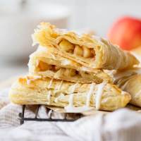 A stack of apple turnovers with one cut in half showing the apple filling.