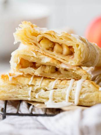 A stack of apple turnovers with one cut in half showing the apple filling.