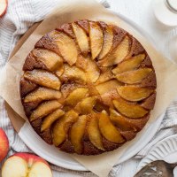 An overhead shot of caramel apple upside-down cake with apples and milk around it.