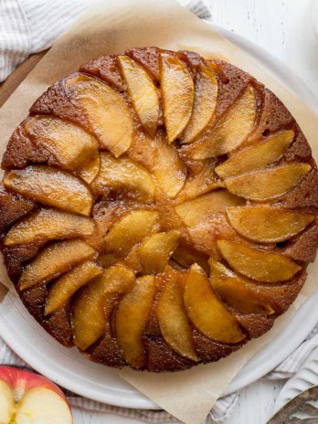 An overhead shot of caramel apple upside-down cake with apples and milk around it.