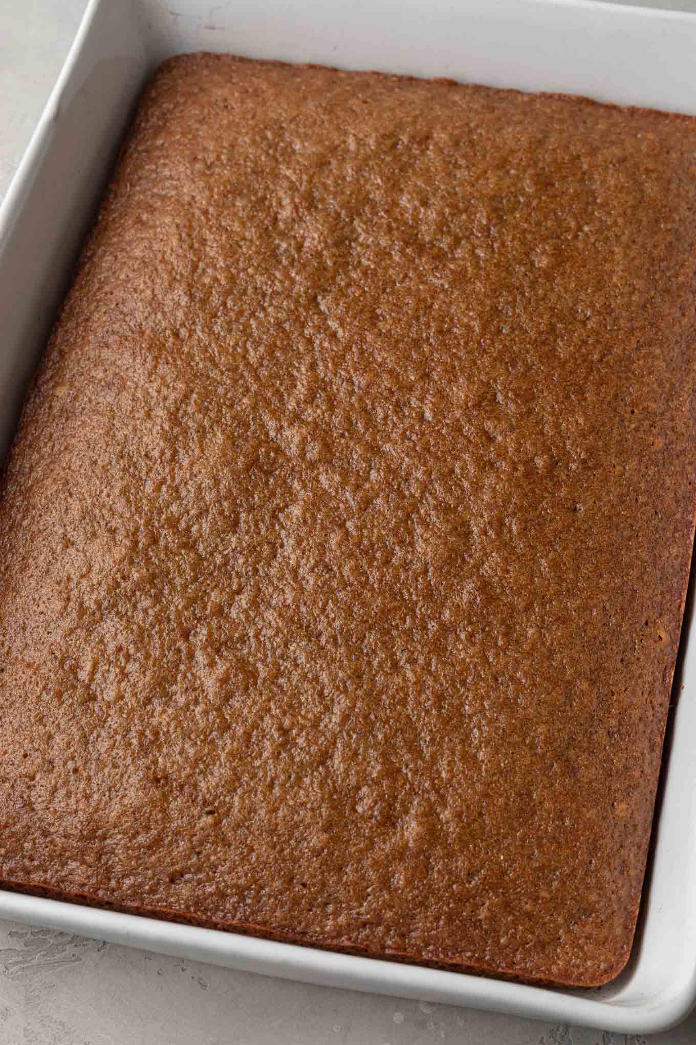 A baked applesauce cake in a white 9x13 baking pan.