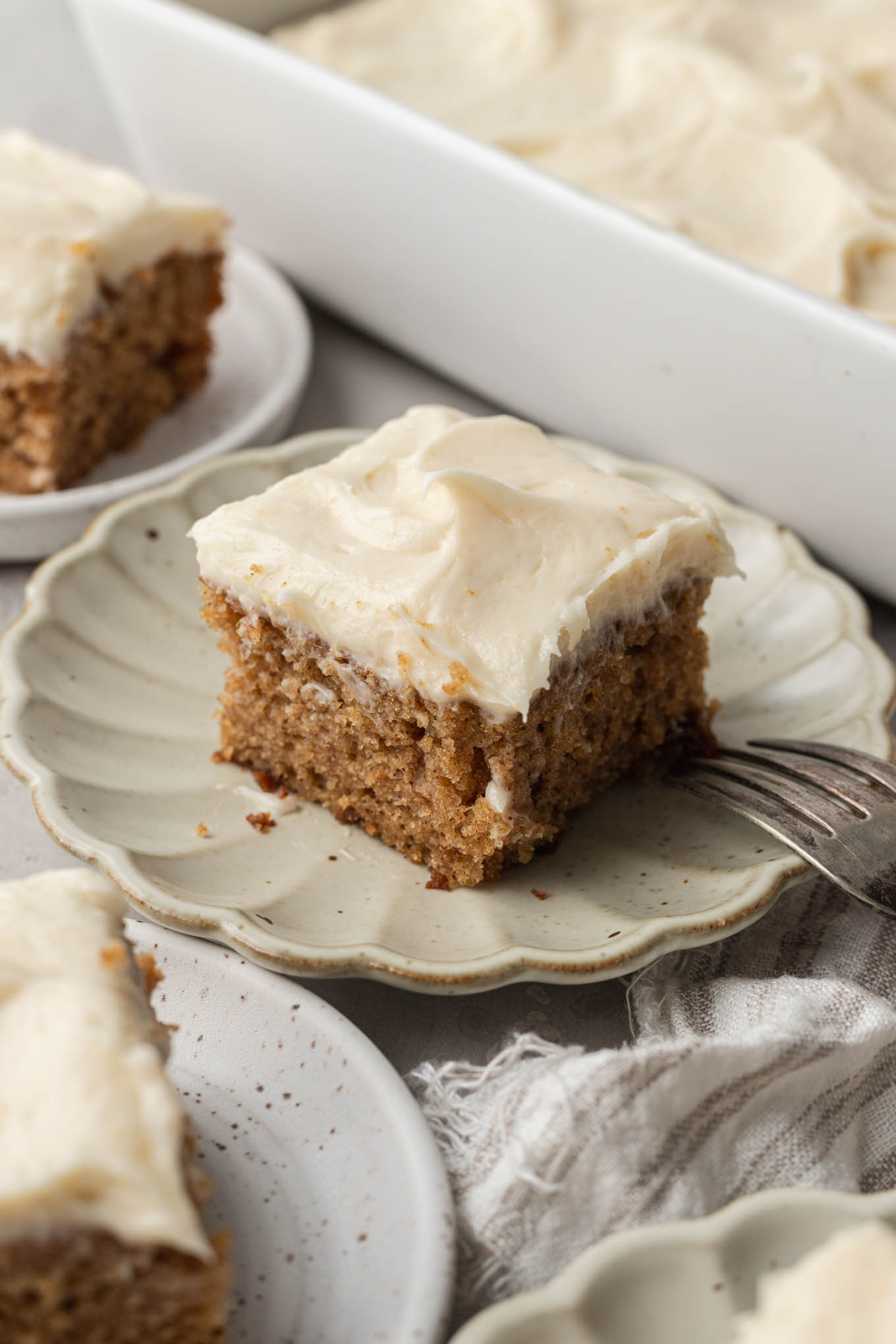 A slice of applesauce cake on a scalloped cream dessert plate. 