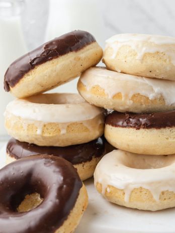 Several baked donuts stacked on top of each other. The donuts are coated in chocolate and vanilla icing.