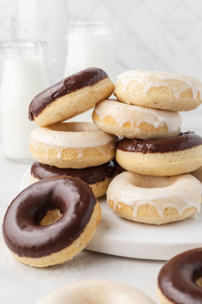 Two stacks of baked donuts with vanilla and chocolate icings. 