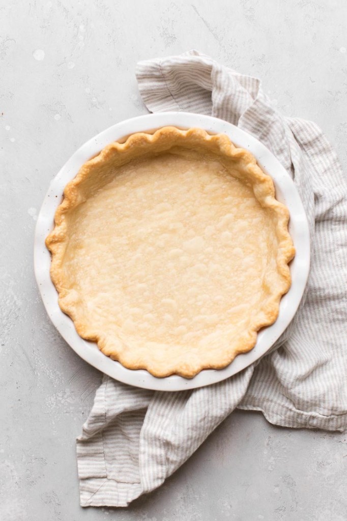 An overhead picture of a blind baked pie crust in a white baking dish.