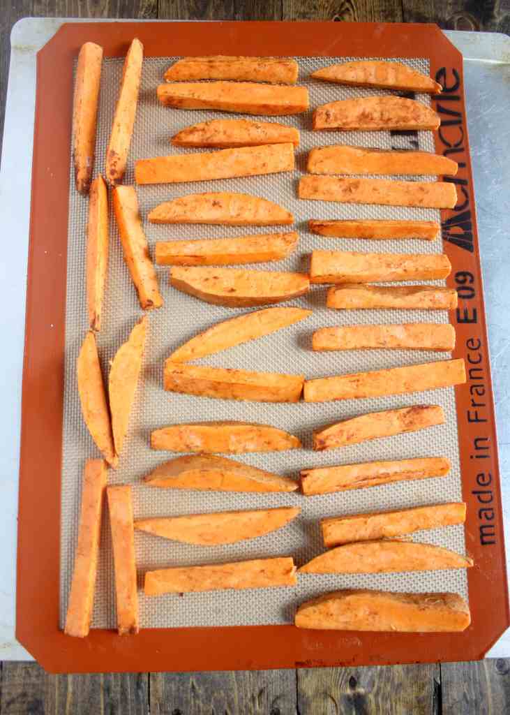 Unbaked sweet potato fries on a Silpat-lined baking sheet. 