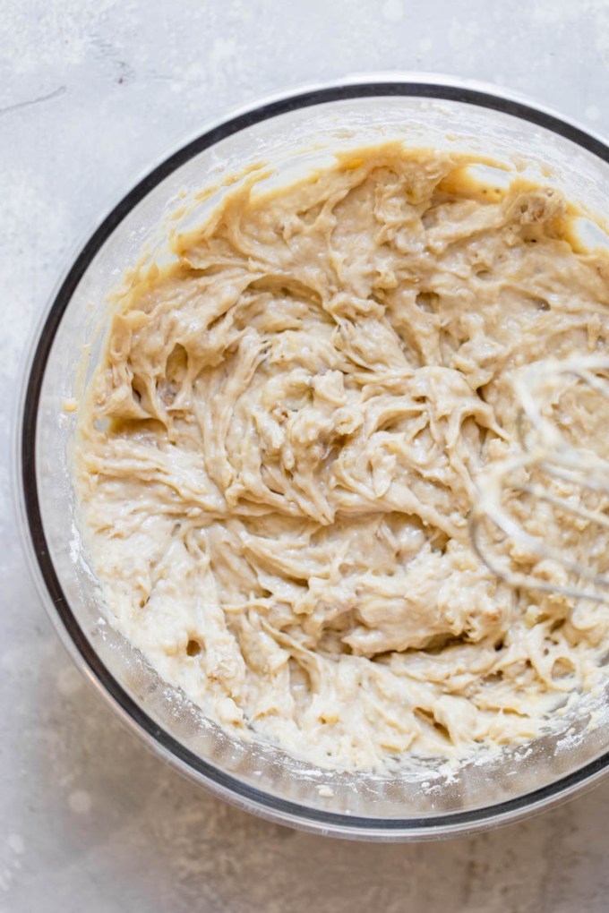 A glass bowl with the finished banana bread batter ready to be poured into a loaf pan.