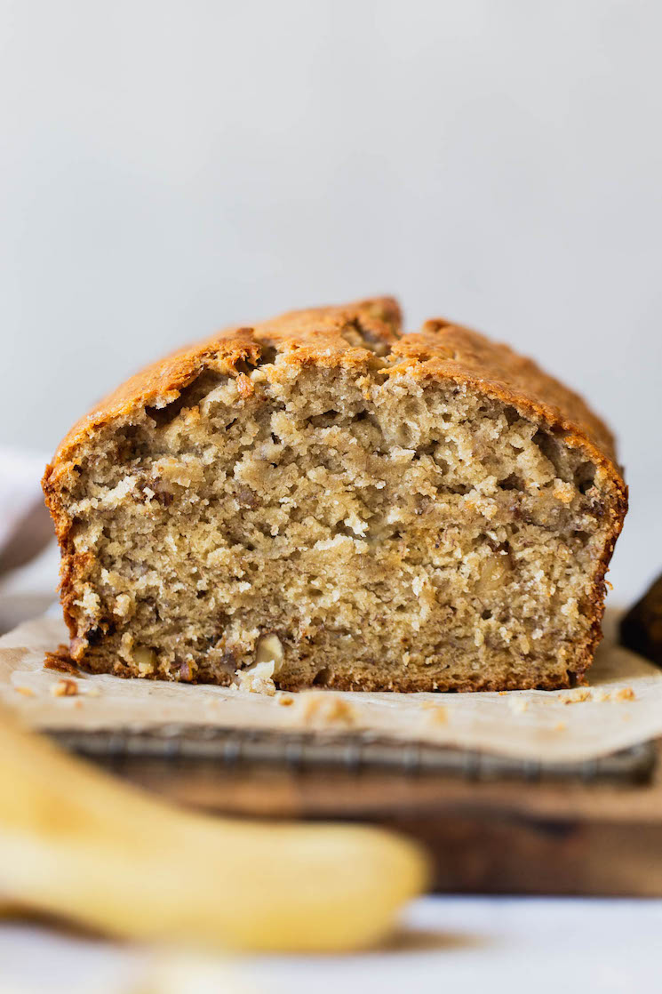 A straight on shot of a loaf of banana bread with the end cut off to show the texture.