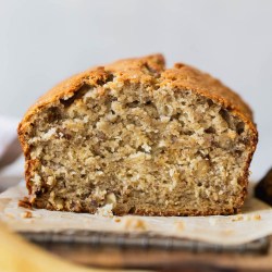 A straight on shot of a loaf of banana bread with the end cut off to show the texture.
