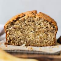 A straight on shot of a loaf of banana bread with the end cut off to show the breads texture.