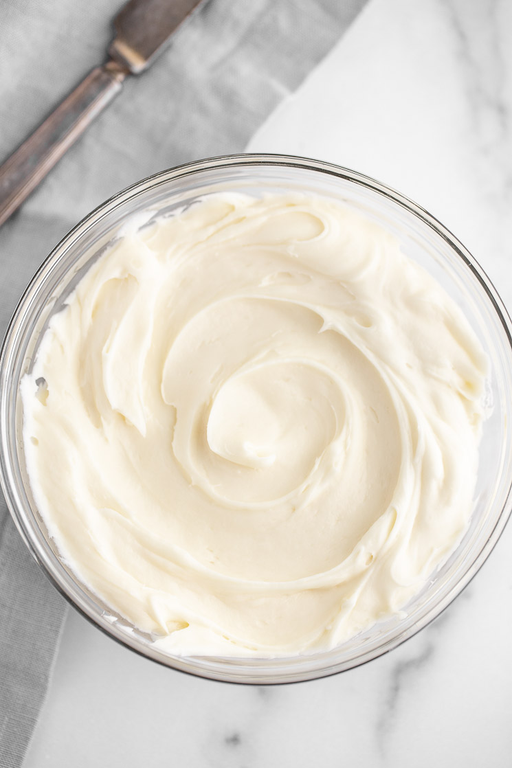 A glass mixing bowl filled with homemade cream cheese frosting.