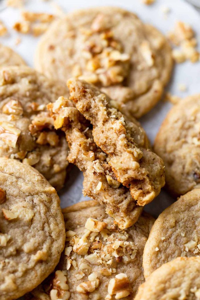 A close-up view of a banana cookie split in half, resting among a pile of cookies. 