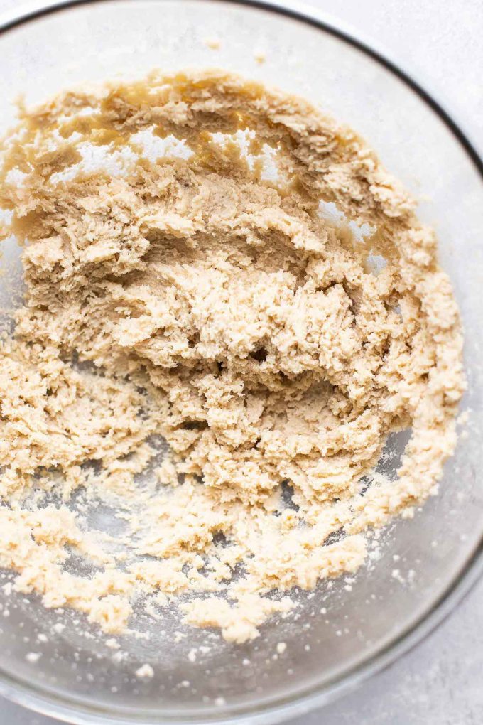 An overhead view of a glass mixing bowl of creamed butter and sugar.