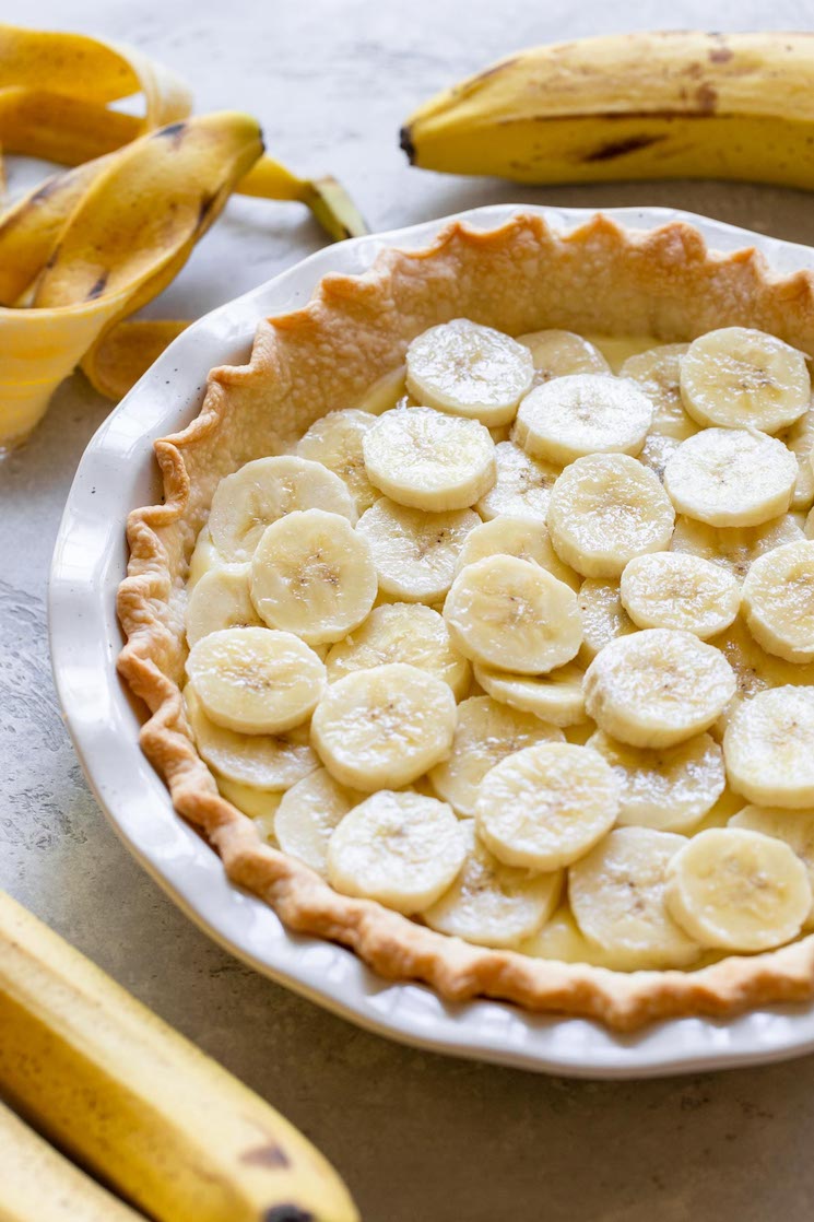 A pie crust filled with a layer of custard filling and sliced bananas.