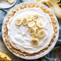 An overhead picture of a finished banana cream pie with extra banana slices on top of the whipped cream.