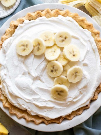 An overhead picture of a finished banana cream pie with extra banana slices on top of the whipped cream.