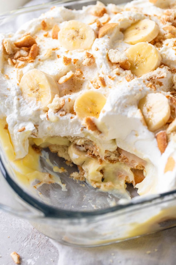 A close up view of a Nilla Wafer banana pudding in a glass dish. A generous serving has been scooped out of the dish. 