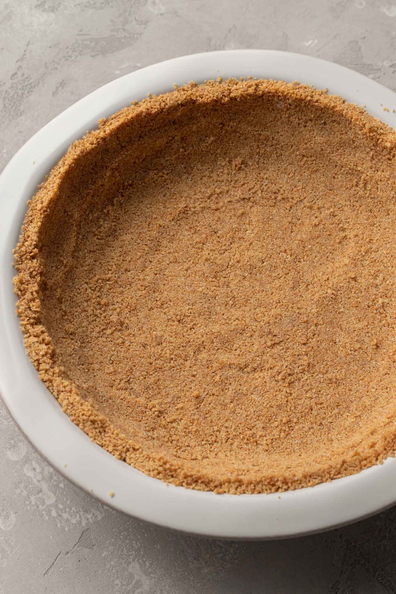 An overhead view of a graham cracker crust in a pie plate. 