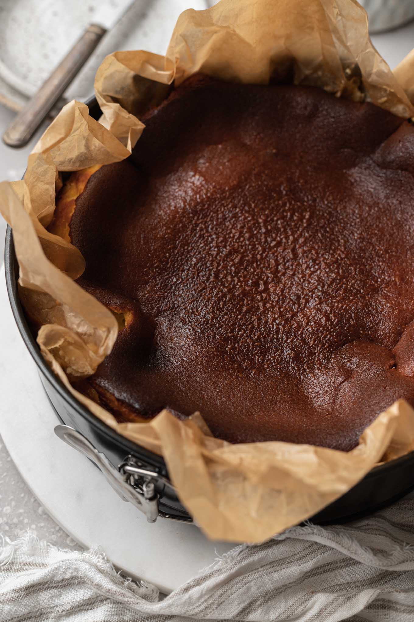 A burnt cheesecake in a parchment-lined springform pan. 