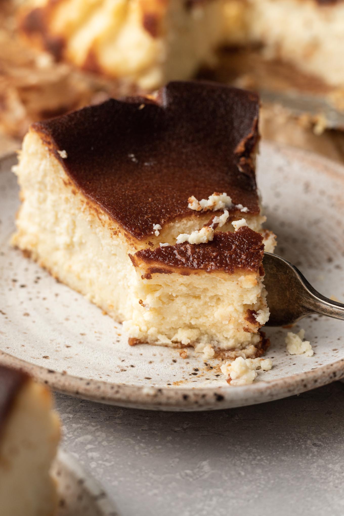 A slice of Basque burnt cheesecake, with a fork cutting a piece off of the end. 