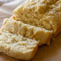 A loaf of beer bread sliced on a piece of parchment paper.