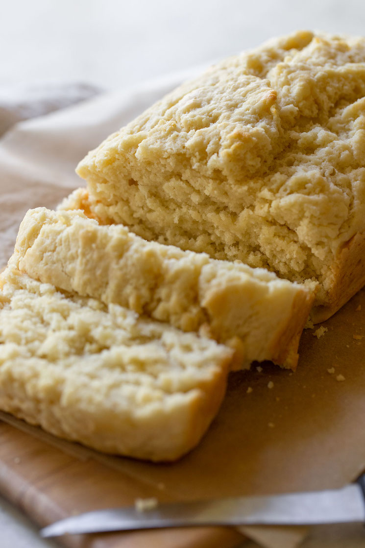 A loaf of beer bread sliced on a wooden cutting board showing the breads texture. 