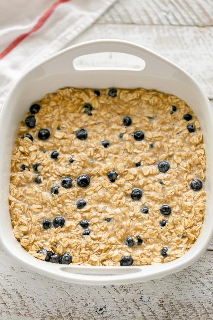 A white baking dish filled with the prepared baked oatmeal mixture.