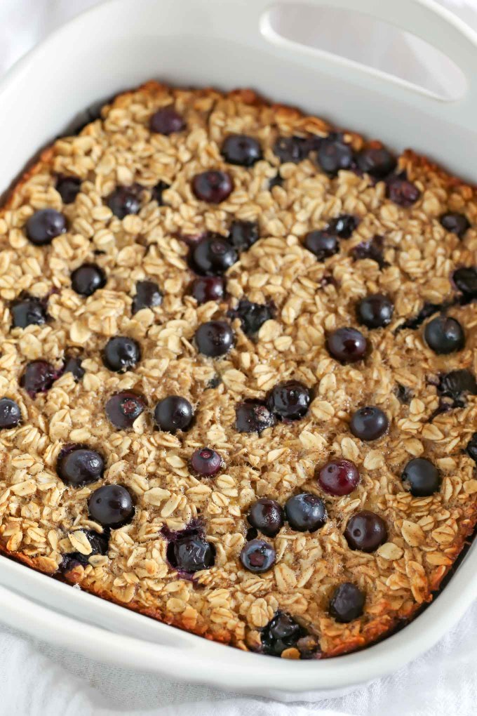 Baked oatmeal studded with blueberries in a white baking dish.
