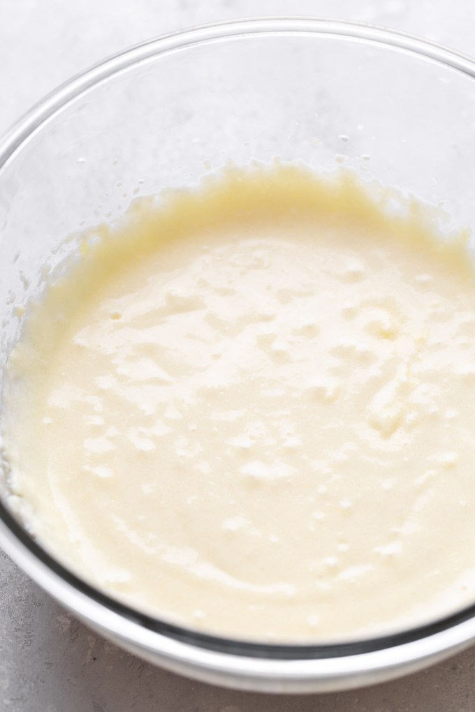 A glass mixing bowl filled with plain cake batter.