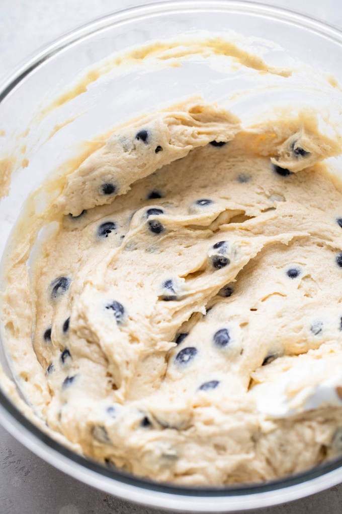 A glass mixing bowl filled with blueberry coffee cake batter.