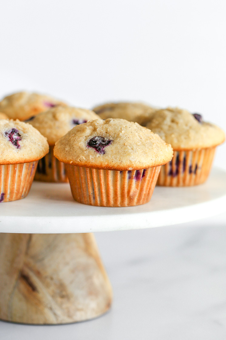 Blueberry muffins on top of a marble cake stand.