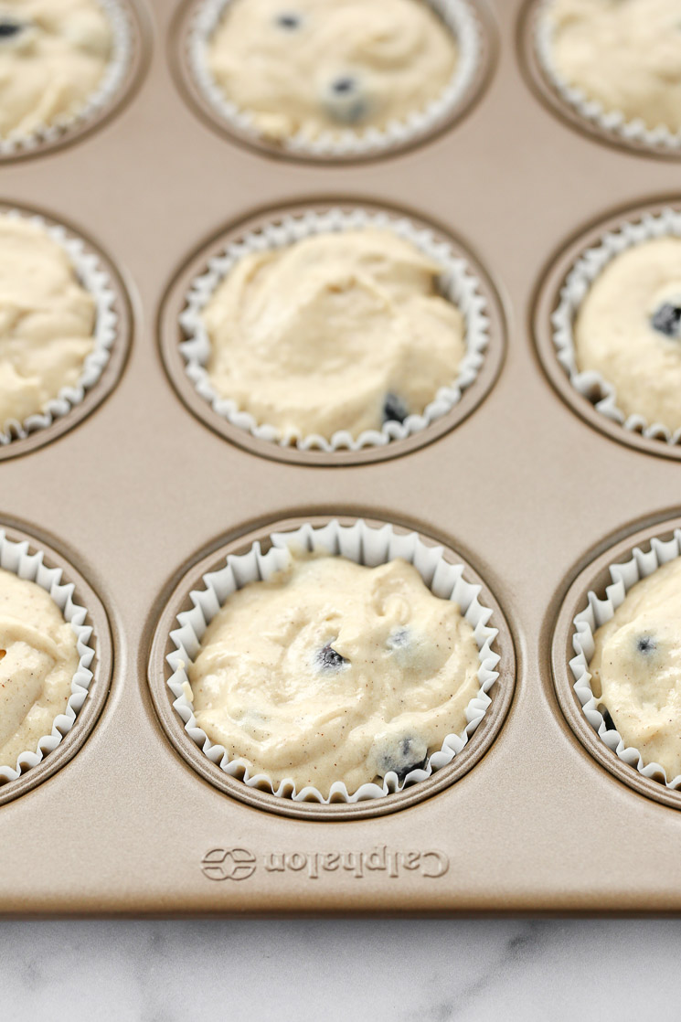 A muffin pan lined with cupcake liners and filled with the muffin batter.