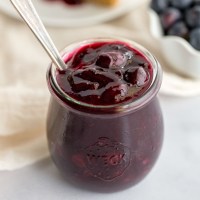 A close-up picture of a jar filled with homemade blueberry sauce.