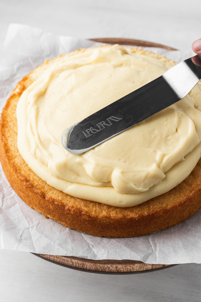 Pastry cream being spread over a sponge cake layer.