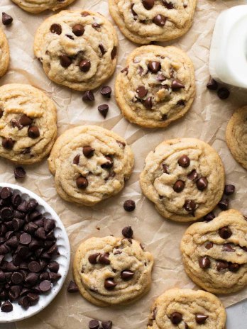 Brown butter chocolate chip cookies laid out on a brown piece of parchment paper.