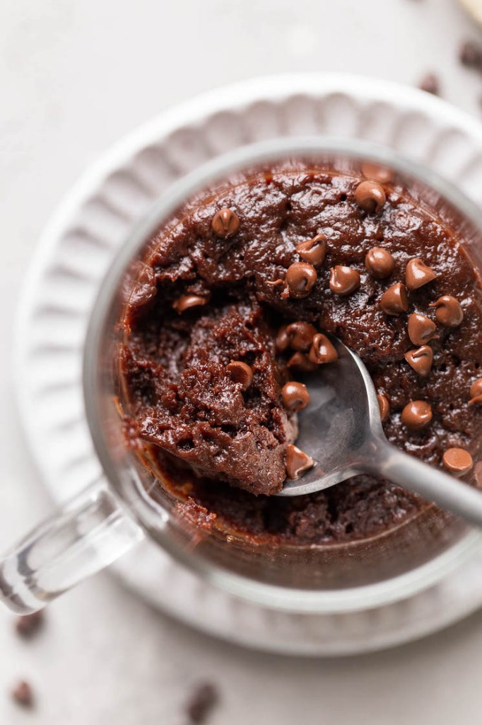 Close up, overhead view of a spoon digging into a microwave mug brownie. 