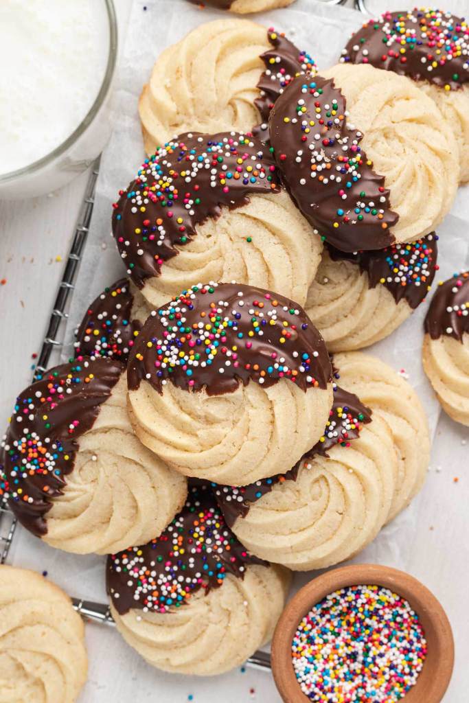 An overhead view of a pile of homemade butter cookies dipped in chocolate. 